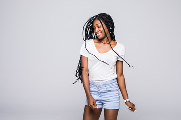 Beautiful Afro American girl is playing with her hair, looking at camera and smiling, isolated on gray background