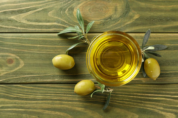 Bowl of fresh olive oil on color wooden table