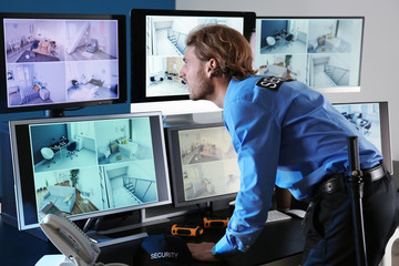 Security guard monitoring modern CCTV cameras in surveillance room