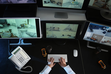 Security guard monitoring modern CCTV cameras in surveillance room