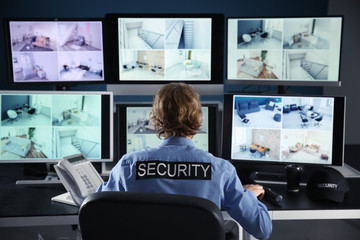 Security guard monitoring modern CCTV cameras in surveillance room