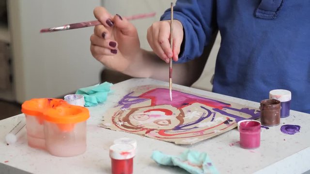 child boy enthusiastically paints with watercolors on paper.