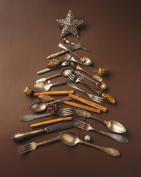 Abstract Christmas tree made from cutlery on a dark brown background. Top view . tree of knives and forks with a star