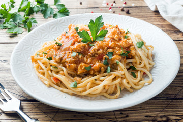 Spaghetti pasta Bolognese on white plate, wooden table