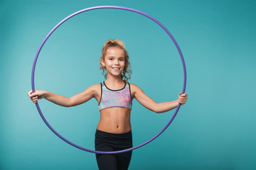 Cheerful little sports girl doing exercises with a hula hoop