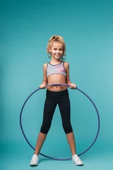Foto op Canvas Cheerful little sports girl doing exercises with a hula hoop © Drobot Dean