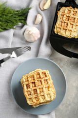 Plate with tasty squash waffles and modern maker on grey table