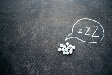 White pills in Z shape and text. Sleeping pills, hypnotic drugs, sedative, melatonin on dark night...