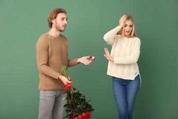 Young woman rejecting marriage proposal on color background