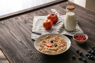 Plate with creative oatmeal for children on dark wooden table