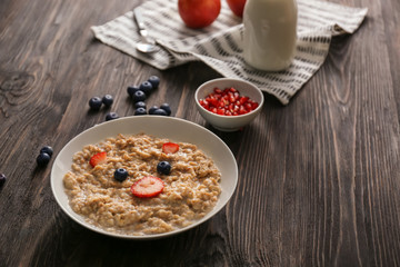 Plate with creative oatmeal for children on dark wooden table