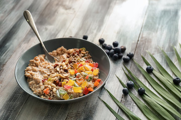 Plate with tasty oatmeal, nuts and succades on wooden table