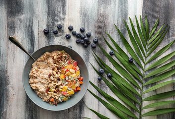 Plate with tasty oatmeal, nuts and succades on wooden table