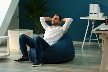 Young businessman sitting on beanbag chair in office