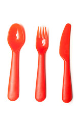 set of orange baby plastic spoon, fork and knife on white background