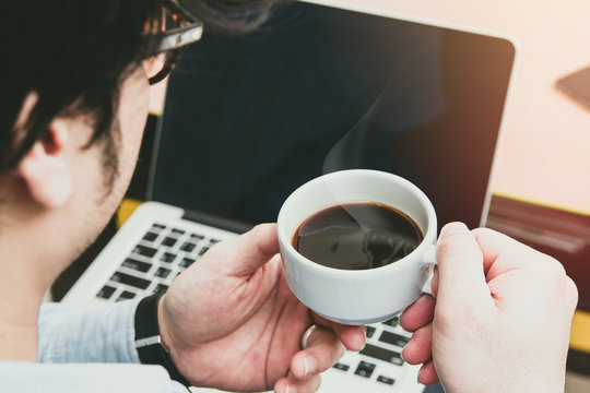 newsletter concept Hand of businessman holding cup of coffee and checking message box on digital laptop in the morning