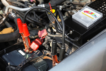 Battery charger under open hood of car