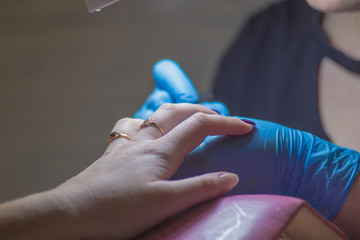 The girl on the manicure. The master covers the nail gel polish. Cosmetic procedures..