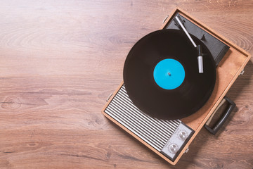 Older Gramophone with a vinyl record on wooden table, top view and copy space.