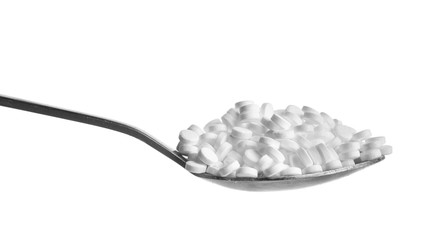 Spoon with sweetener tablets on white background