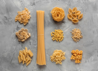 Obraz na płótnie Canvas Different types of raw pasta on grey background