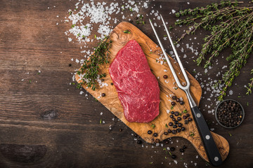 delicious raw beef sliced on a wooden background with herbs