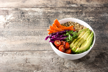 Vegan Buddha bowl with fresh raw vegetables and quinoa on wooden table. Copyspace

