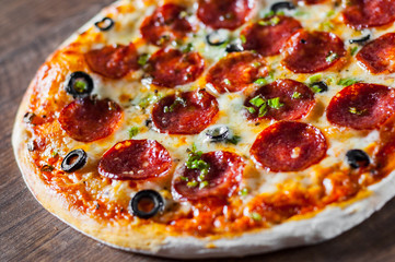 Pizza with Mozzarella cheese, pepperoni, tomato, pepper, olive, salami. Italian pizza on wooden table background