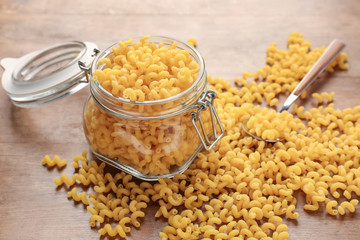 Jar with raw pasta on wooden table