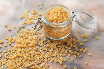Jar with raw pasta on color table