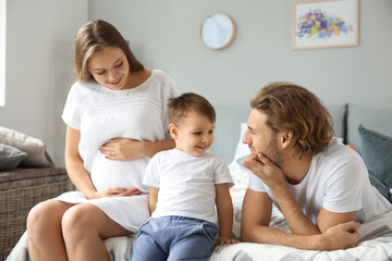 Young pregnant woman with her family in bedroom