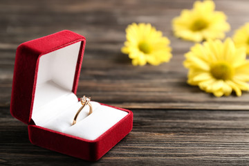 Box with beautiful engagement ring on wooden table