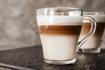 Glass cups of tasty aromatic latte on slate plate