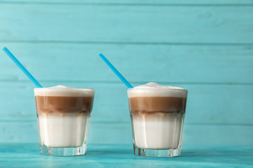 Glasses of tasty aromatic latte on color table