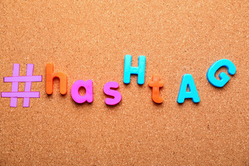 Hashtag composed of letters on cork background