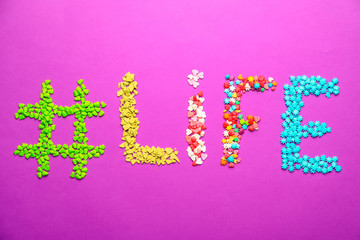 Hashtag LIFE made of sprinkles on color background