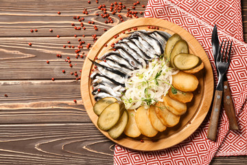 Tasty sprats with potato, onion and pickles on table