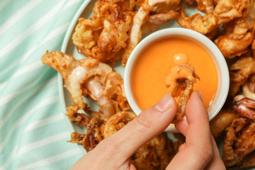 Woman eating tasty fried squid with sauce, closeup © Pixel-Shot
