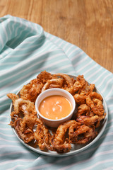 Tasty fried squid with sauce on table