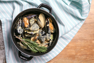 Tasty mussels in pot on table
