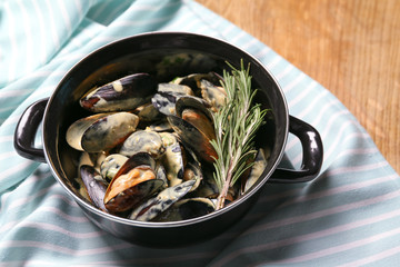 Tasty mussels in pot on table