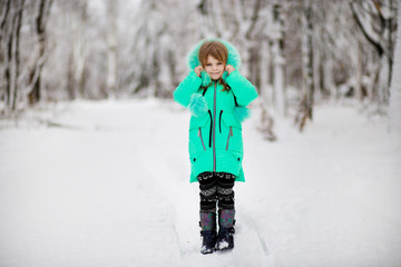 Funny little girl having fun in beautiful park during snowfall