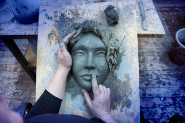 the hands of the sculptor mold the mask