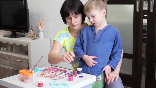 child boy enthusiastically paints with watercolors on paper.
