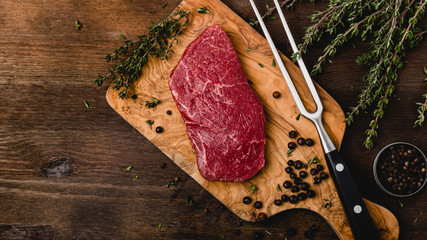 delicious raw beef sliced on a wooden background with herbs