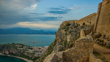 Fototapeta na wymiar fortress ruin on top of rock above sea and medieval small city alone bay shoreline