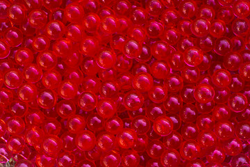 Water red gel balls with bokeh. Polymer gel. Silica gel. Balls of red hydrogel. Crystal liquid ball with reflection. Red texture background. Macro