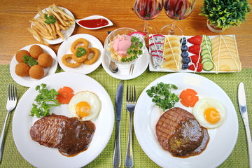 A two man steak dinner with side dishes