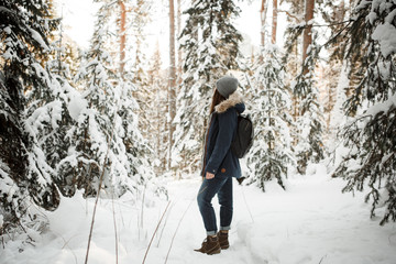 Beautiful young girl in a winter park walks in the winter forest