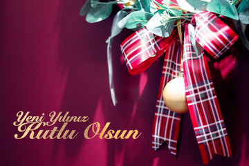 Red christmas gift ribbon on red background with text. Yeni yılınız kutlu olsun means happy new year